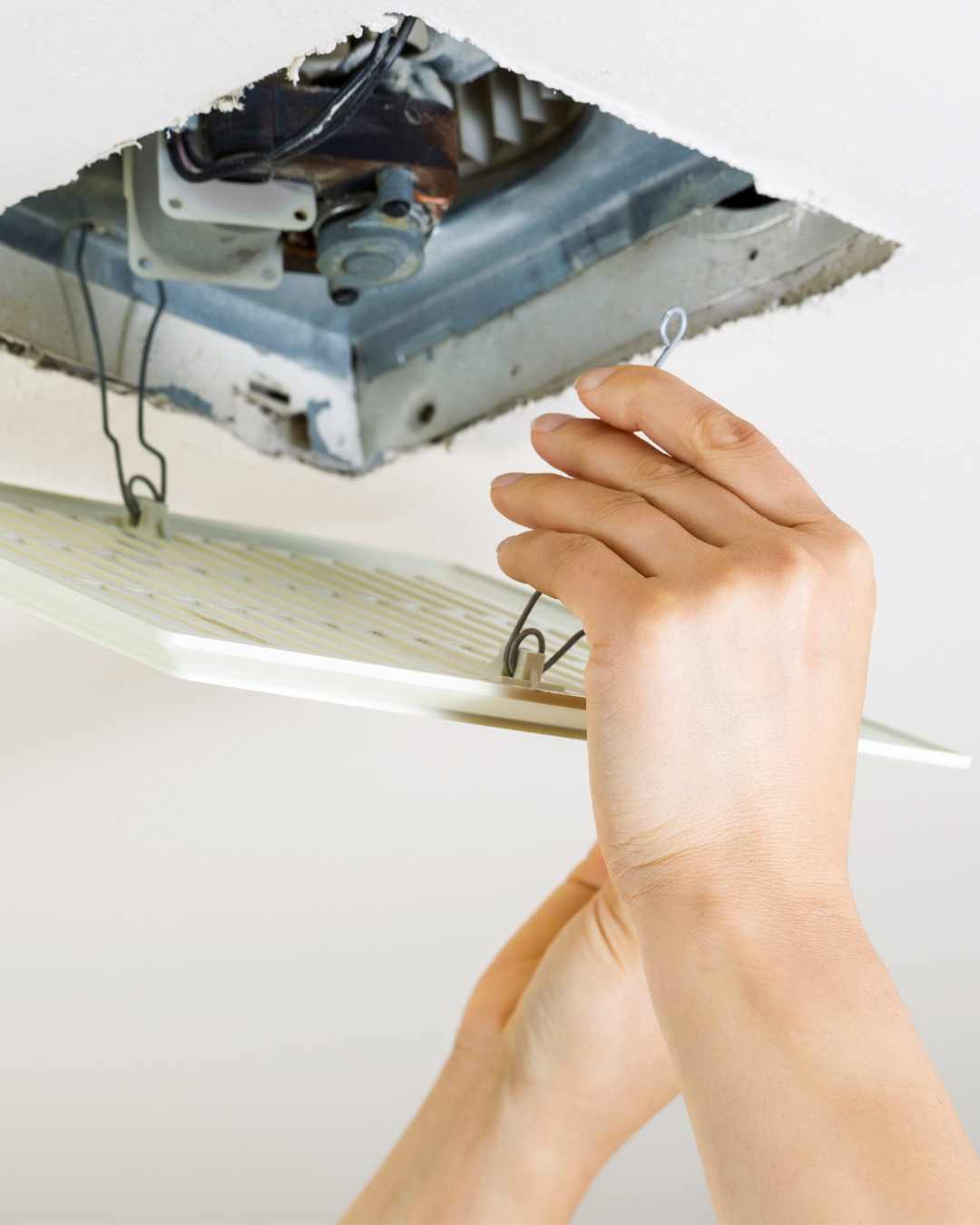 Technician installing a bathroom exhaust fan and ductwork to improve ventilation and reduce moisture buildup.