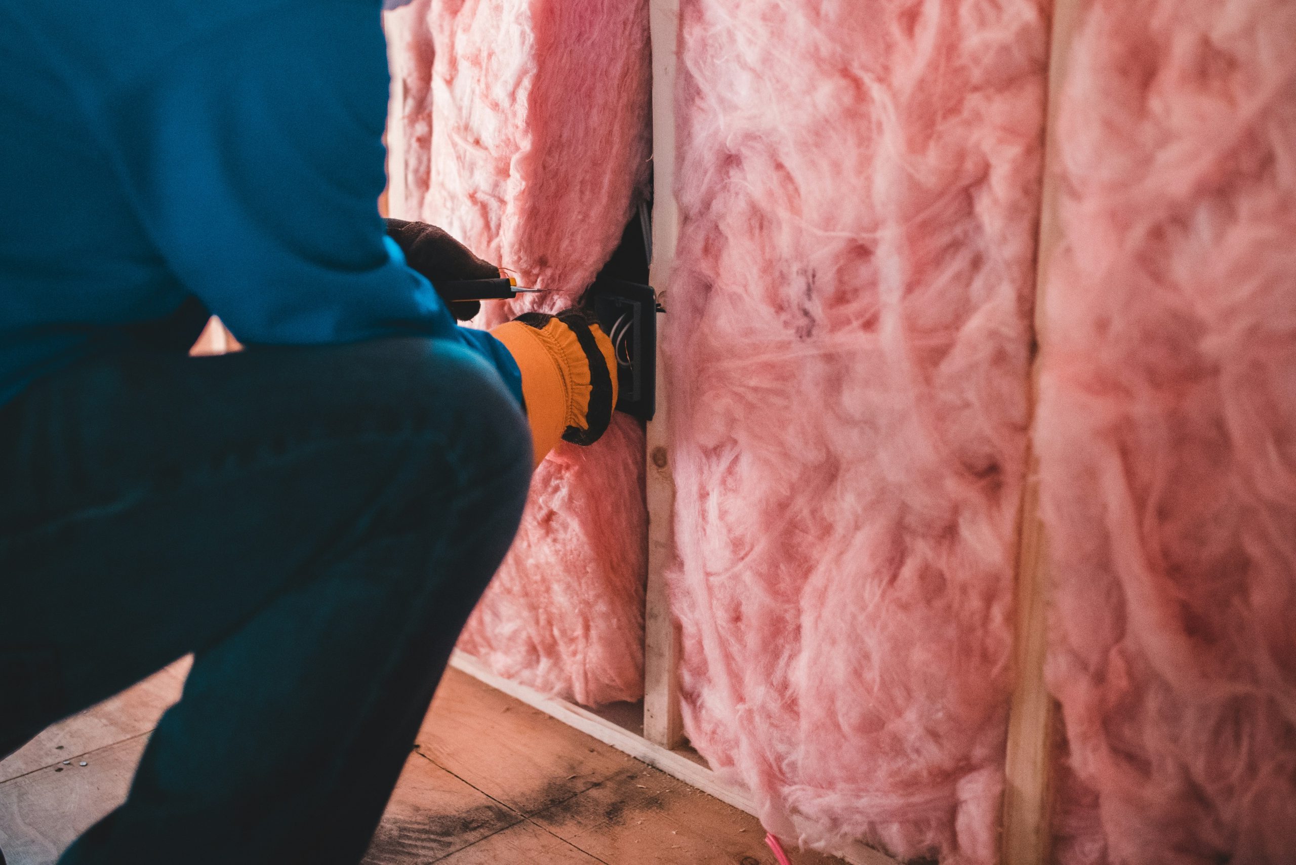 professional is installing batt insulation into the studs of a home to help with climate control
