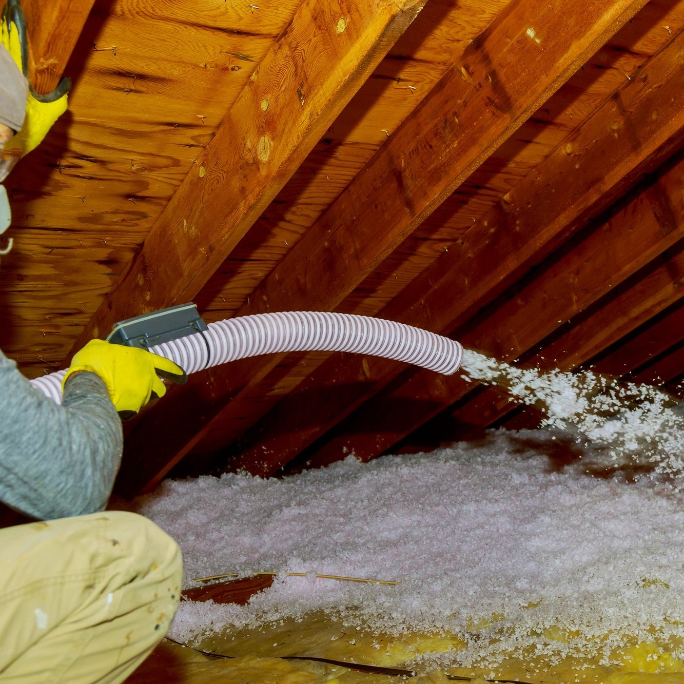 Technician spraying Fiberglass blown in Insulation between Attic Trusses foam insulation repair tool in